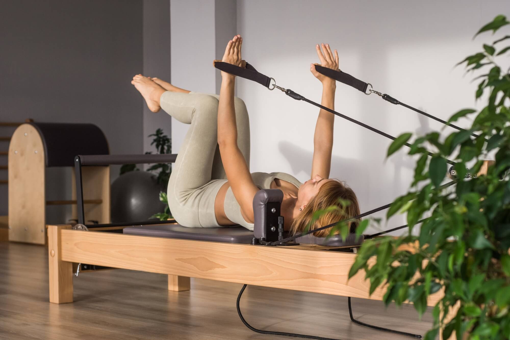 Woman training pilates on the reformer bed. Reformer pilates studio machine for fitness workouts in